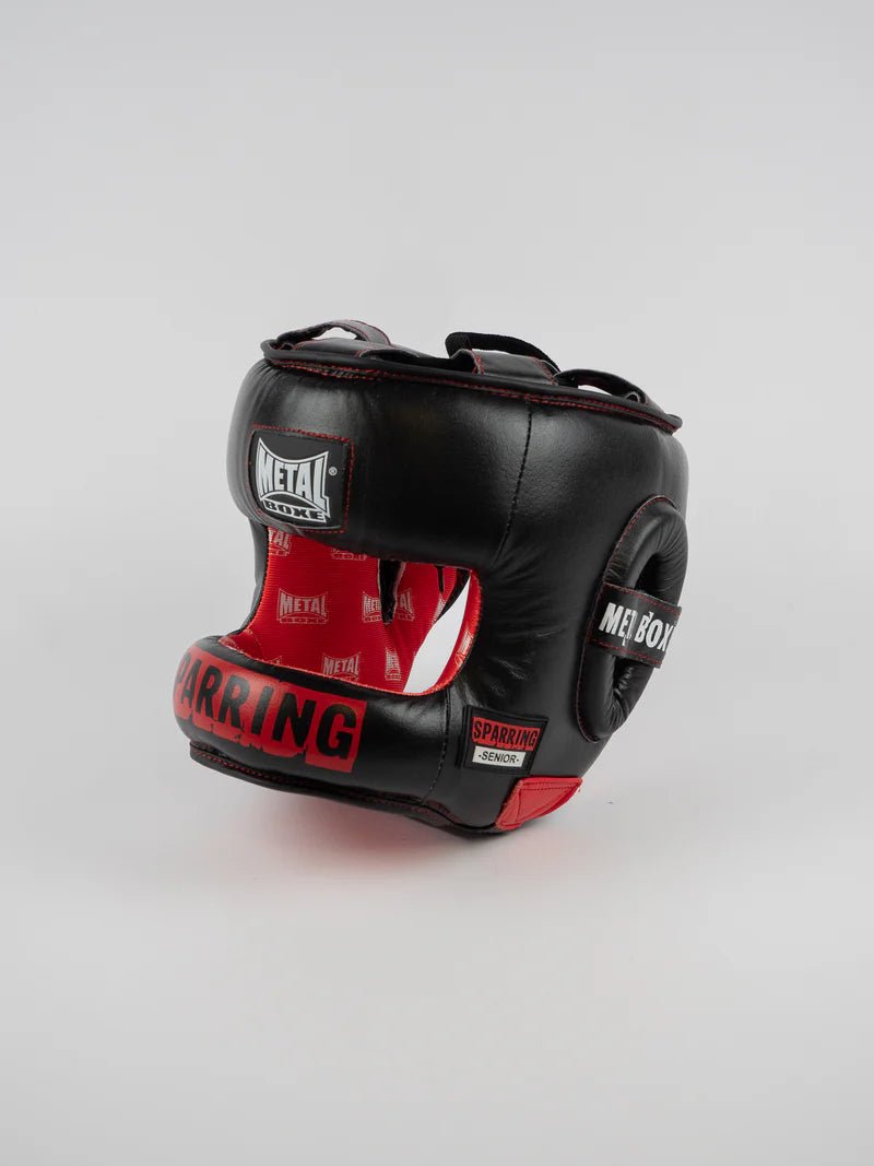 Framifrån av den svarta Metal Boxing Senior Sparring-hjälmen med skyddsstång och röda detaljer