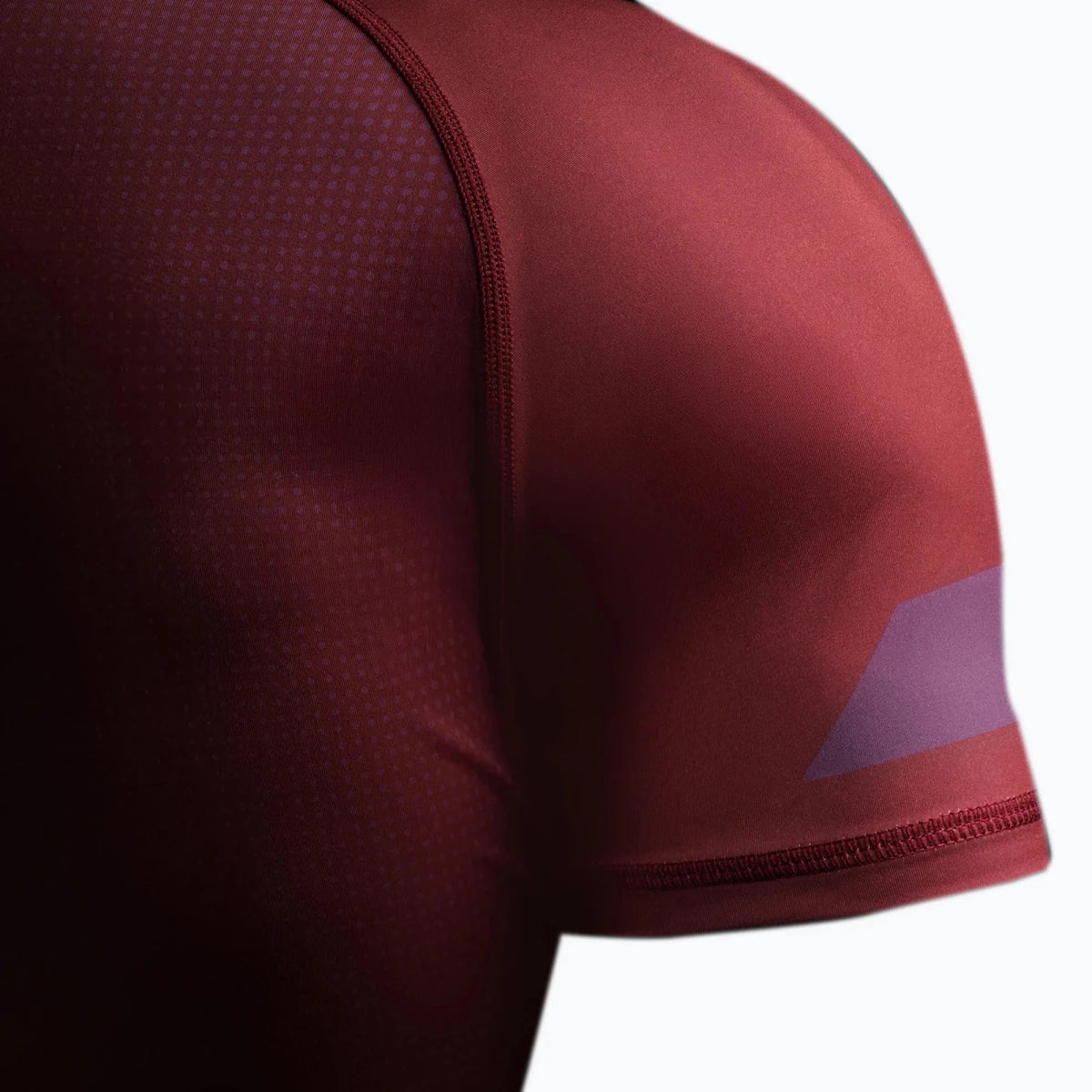 Détail du bord antidérapant en silicone sur le rashguard bordeaux.
