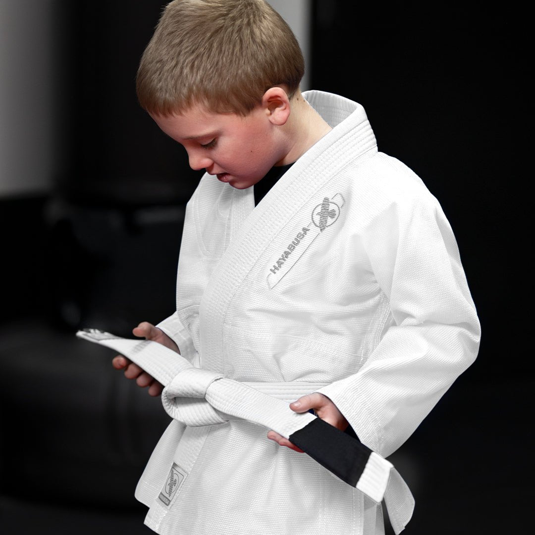 Ett barn som tränar på tatami i den vita Hayabusa Essential BJJ-kimonon