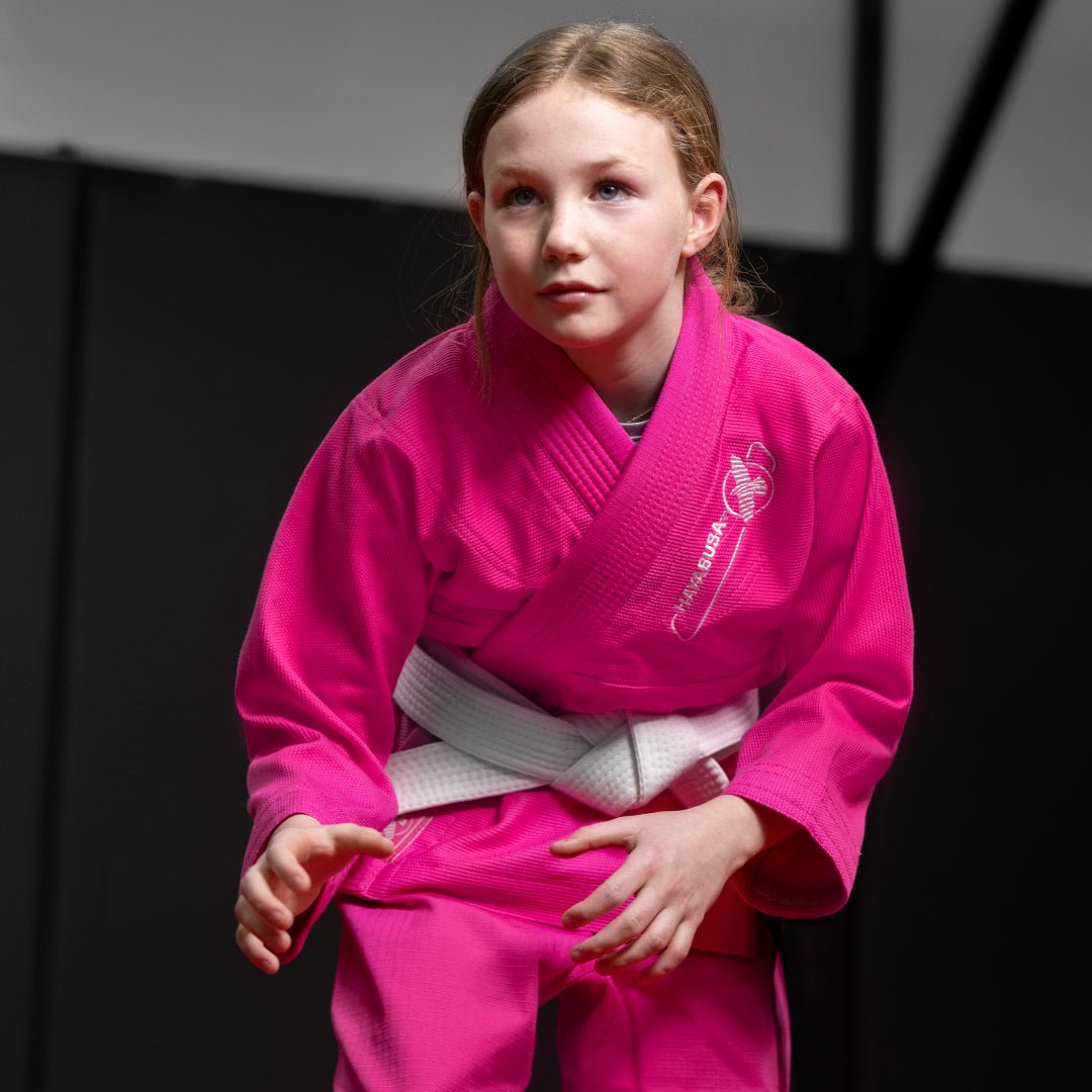 Liten flicka under en Jiu Jitsu-session som bär den rosa Hayabusa Essential-kimonon