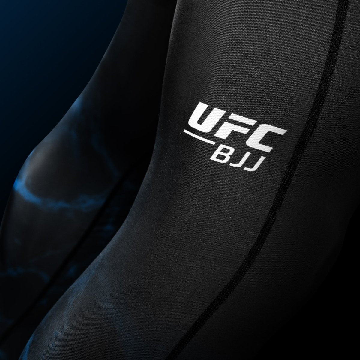 Detalhe em close da escrita do UFC impressa na perna da legging BJJ Spats preta e azul