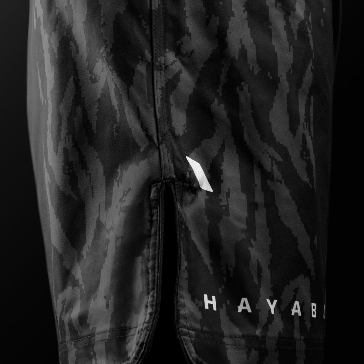 Sidovy av de svarta Hayabusa Apex Mid-Thigh MMA-shortsen med ventildetalj för maximal rörlighet