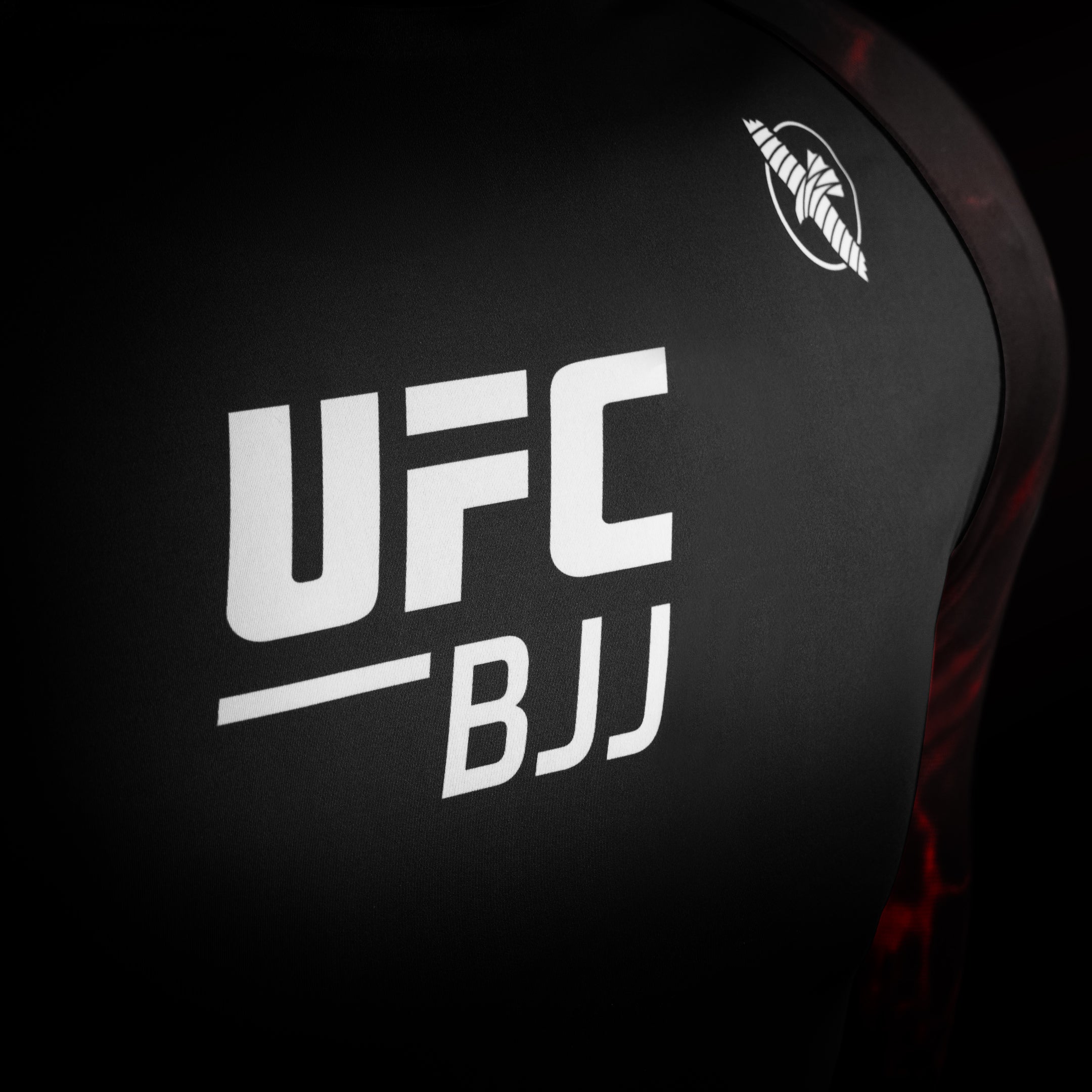 Dettaglio del logo ufficiale UFC sulla rash guard da competizione nera e rossa