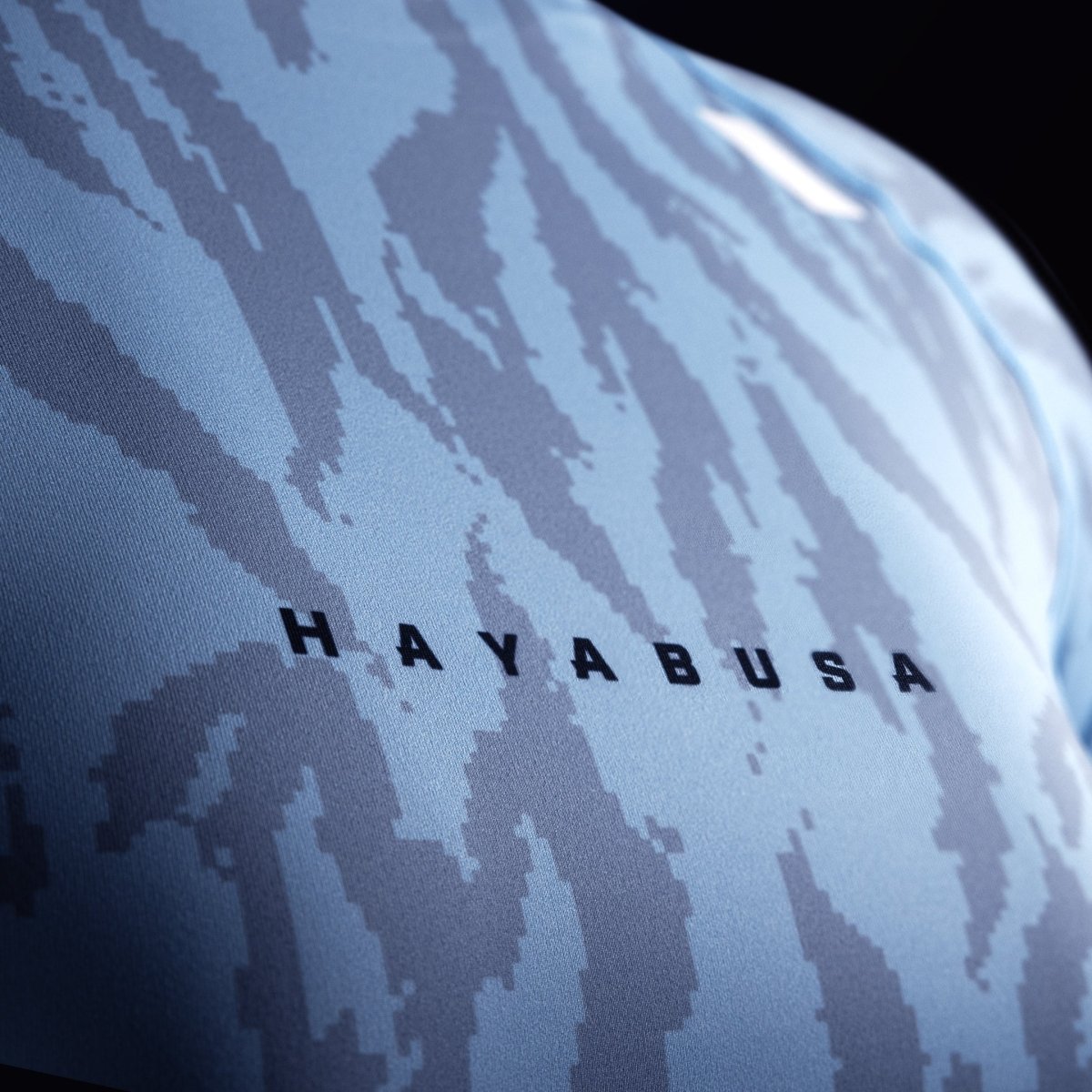 Detail van het Hayabusa-schrift op de borst van de lichtblauwe rashguard, focus op het weefsel van de 200 GSM-stof