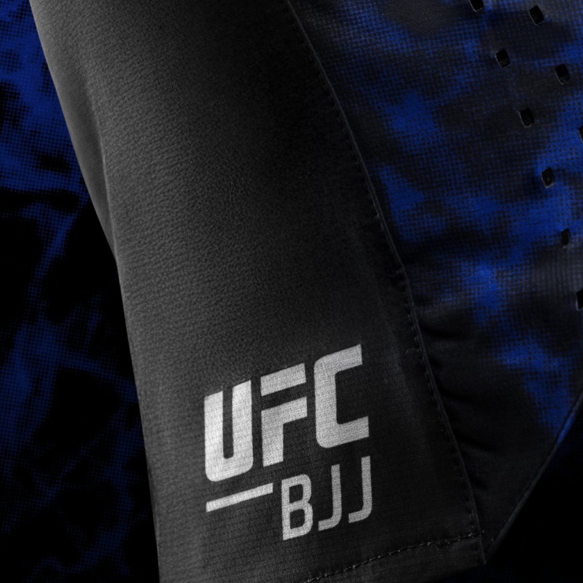 Détail latéral du logo officiel de l'UFC BJJ imprimé sur le short noir et bleu pour femme