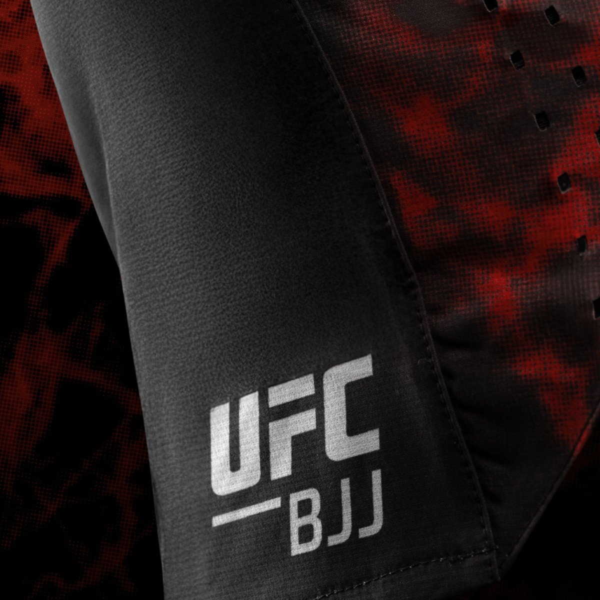 Gros plan du logo latéral UFC BJJ sur un short de grappin noir et rouge pour femme