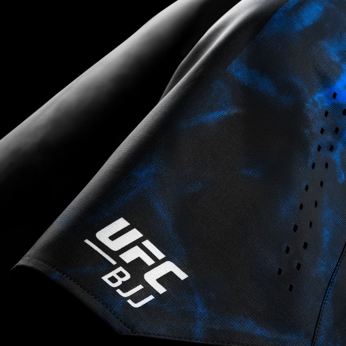 Detail logo dan grafis UFC BJJ pada celana pendek kompetisi berwarna hitam biru