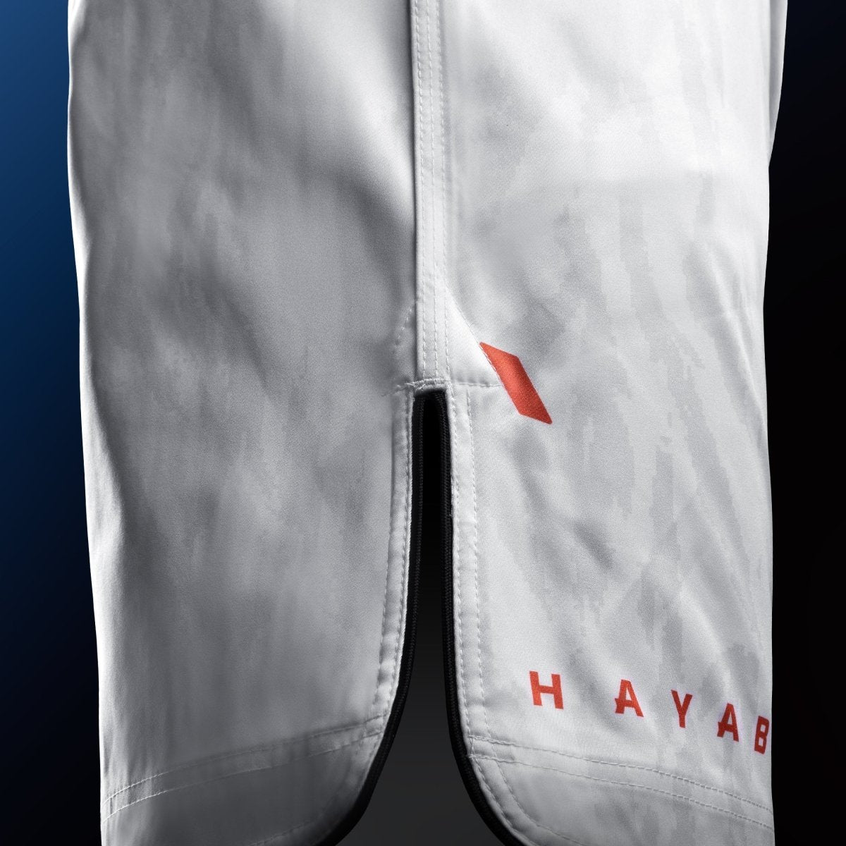 Sidovy av de vita Hayabusa Apex Mid-Thigh MMA-shortsen med ventildetalj för maximal rörlighet
