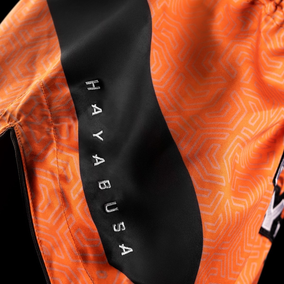 Detail lesklého provedení a odolnosti látky u oranžových kraťasů Hayabusa Core